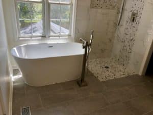 This image features a curbless shower next to a white bathtub.